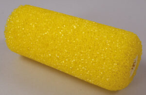 En gul malerrulle med en ru overflade ligger på en lys baggrund.