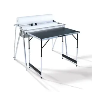 Et bord med hvid ramme og sort bordplade holder en stor papirholder med hvid papir på toppen. Bordet står i et enkelt og lyst rum.